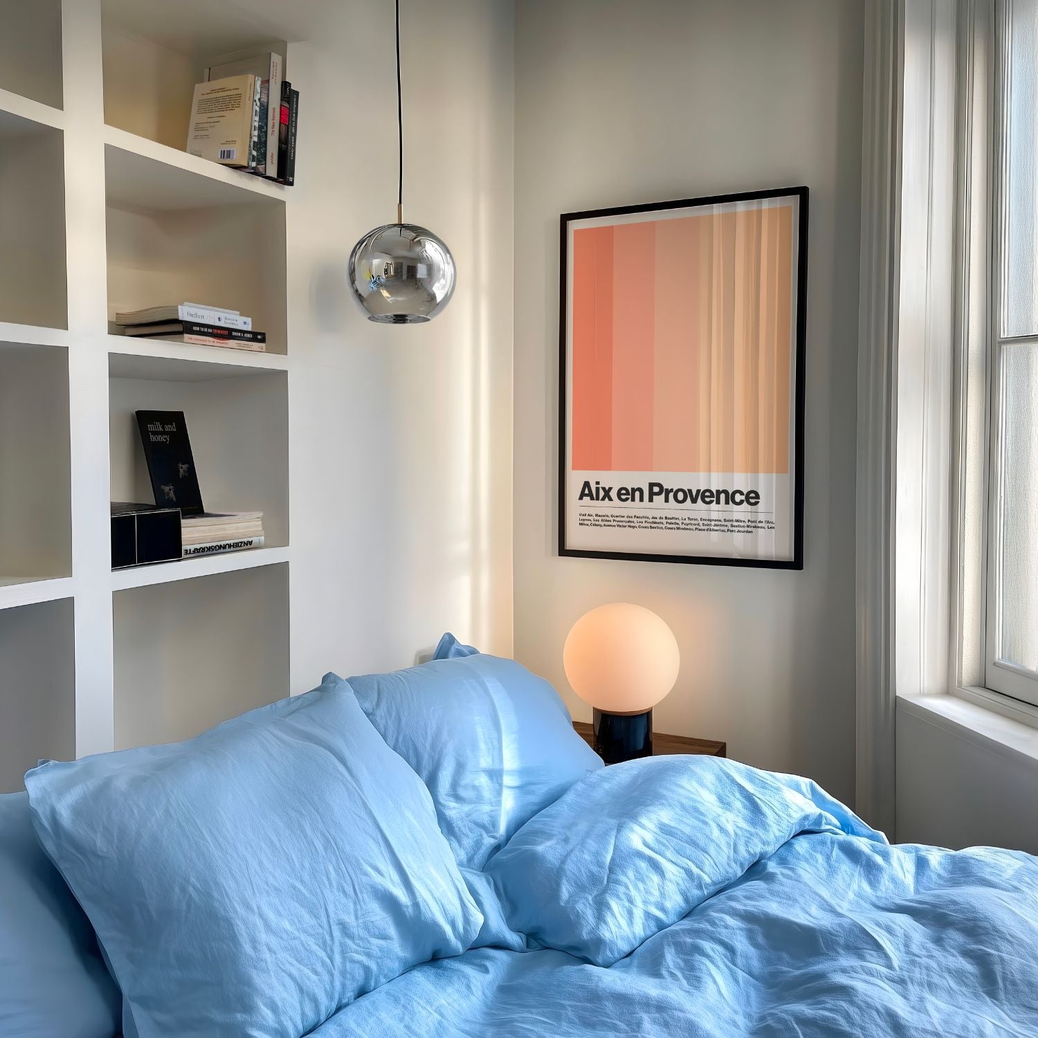 Bedroom with blue bedding, bookshelf, and wall art
